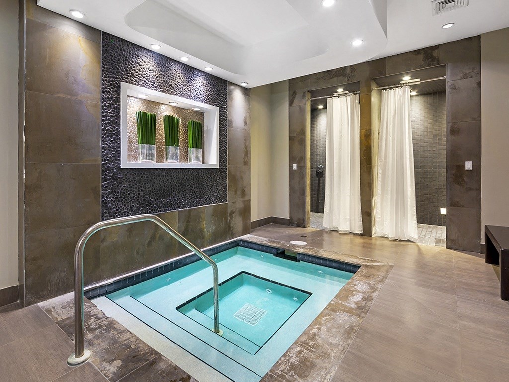 a swimming pool in the middle of a room with a shower and a bench