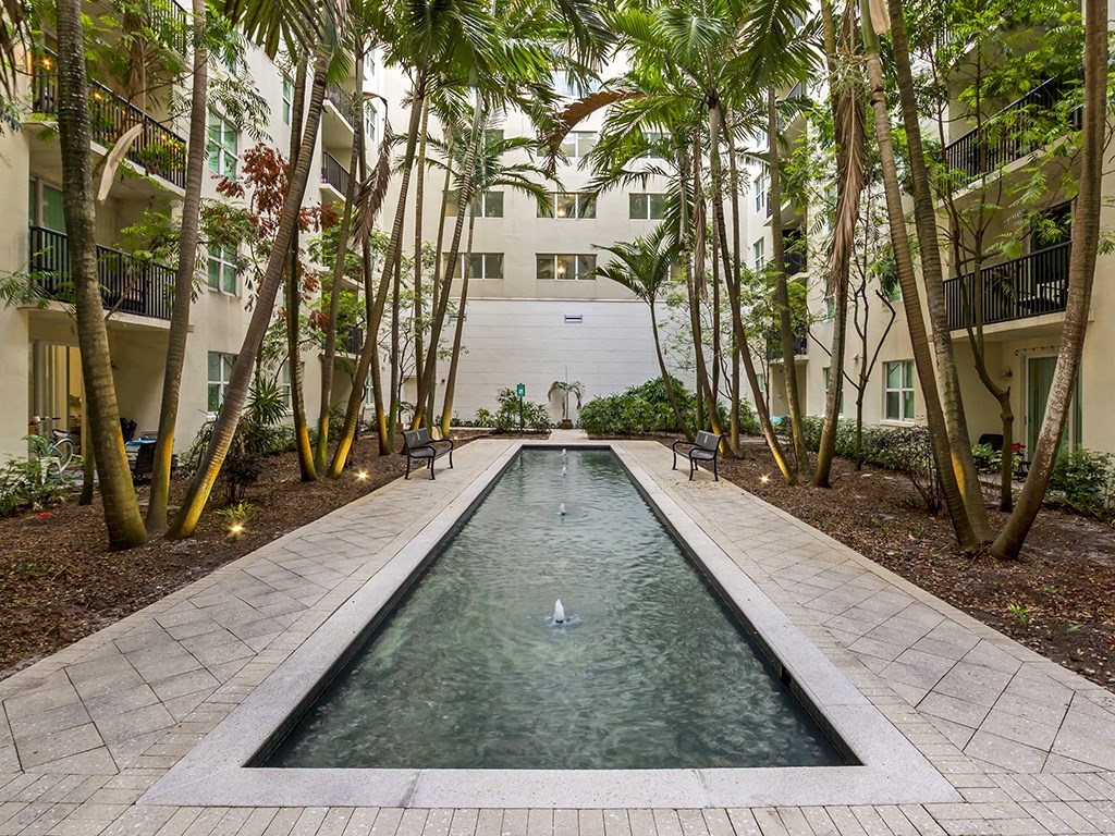 a courtyard with a water feature and a white building in the background