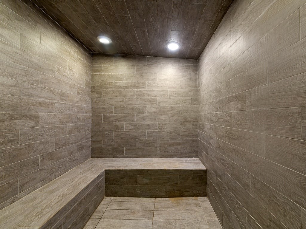 a large shower with tiled walls and a wooden ceiling
