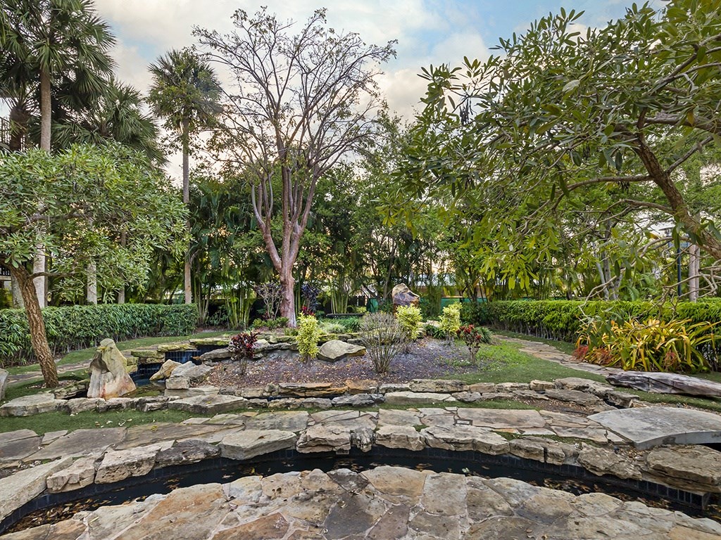 a pond in a garden with trees in the background