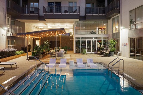 A pool area with chairs and a building in the background.
