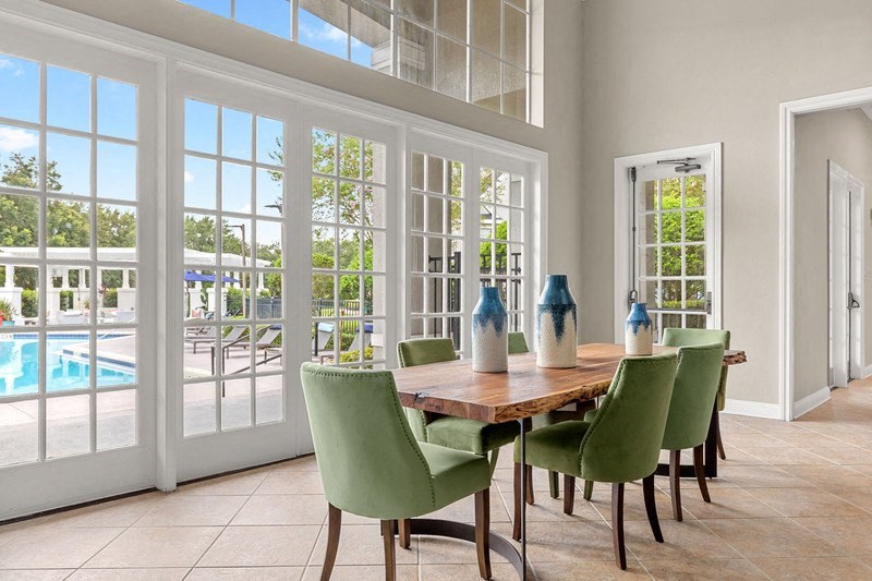 a dining room with a table and chairs and a pool in the background