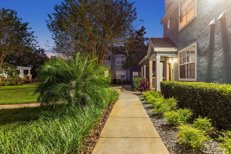 a sidewalk leading to a house with a light on