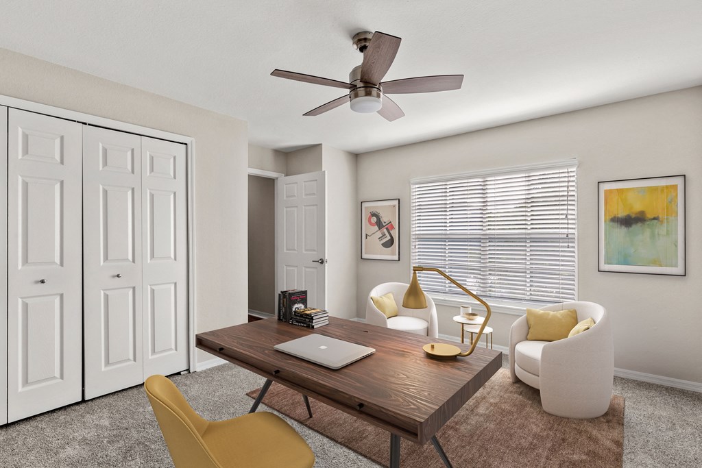 a living room with a desk and a ceiling fan