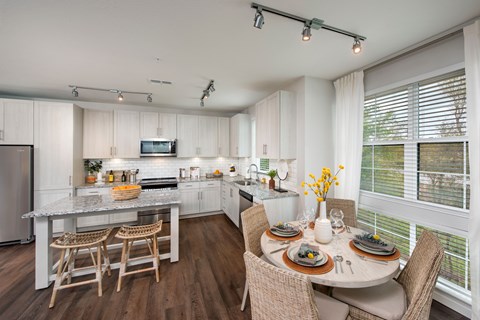 A modern kitchen with a dining table set for two.