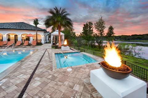 A fire pit is on a patio next to a pool.