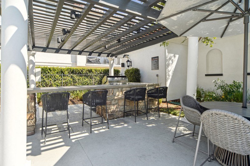 a patio with a bar and chairs and an umbrella