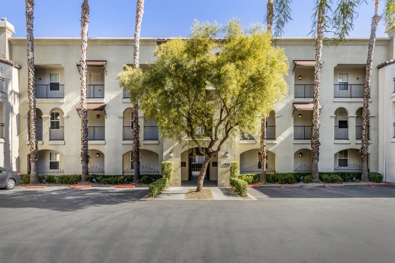 a white apartment building with trees and a street in front of it