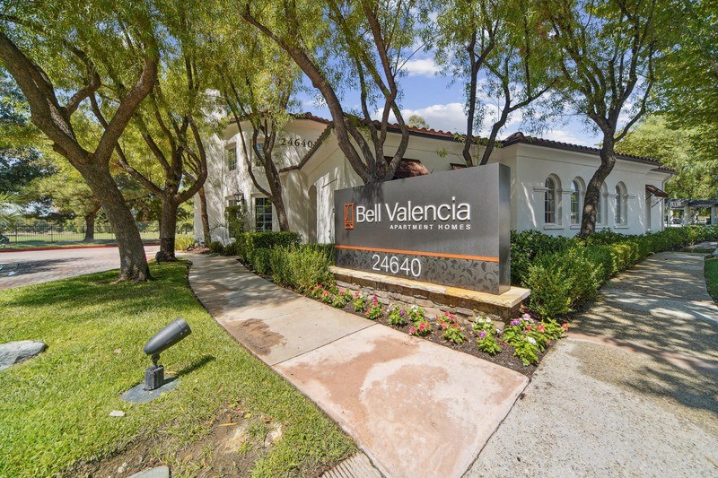 a sign in front of a building with trees and a sidewalk