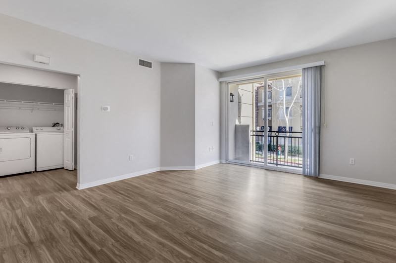 an empty living room with a large window and wood flooring