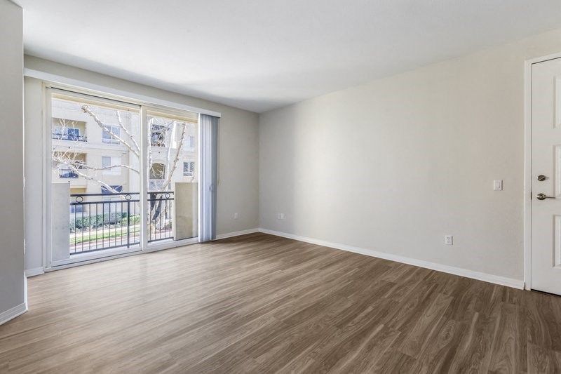 an empty living room with a door to a balcony