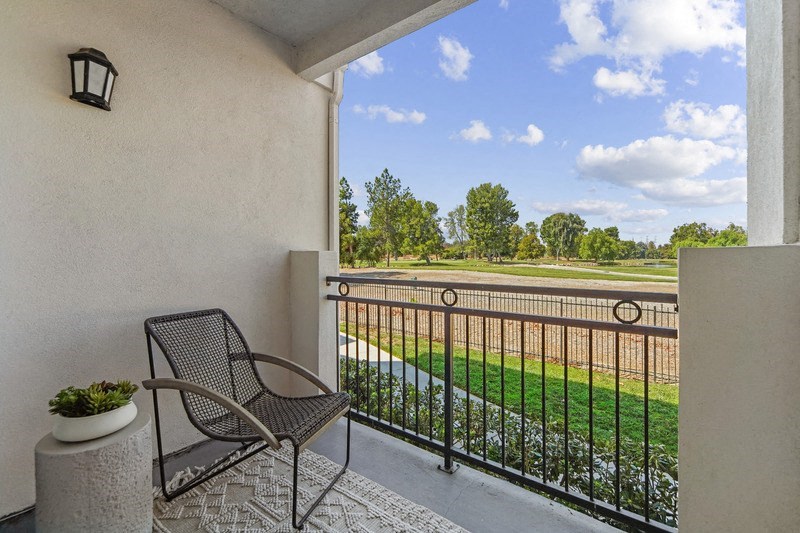 a balcony with a chair and a view of a field