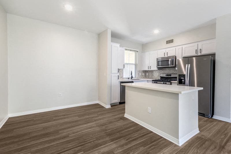 an empty kitchen with a stainless steel refrigerator
