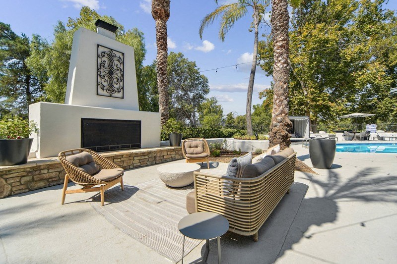 a patio with chairs and a fireplace next to a pool