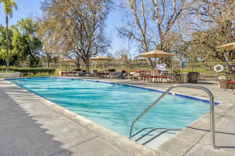 a swimming pool with tables and umbrellas next to it