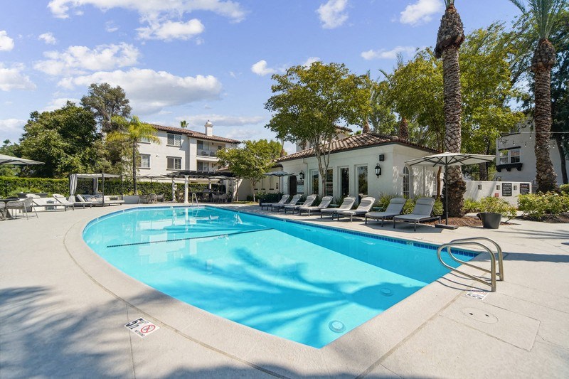 a swimming pool with lounge chairs around it in front of a building