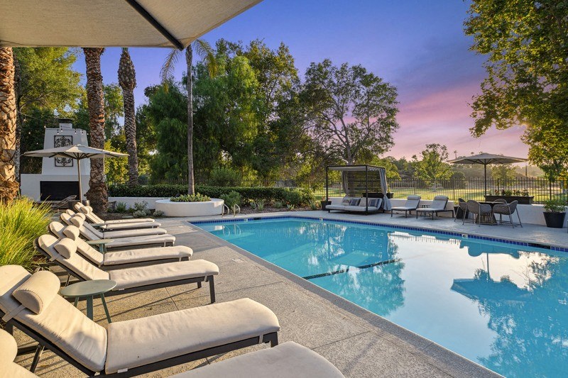 Pool with chairs surrounding it and trees in the background.