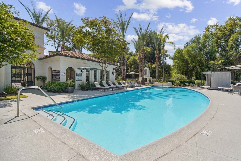 a swimming pool with chairs around it in front of a building