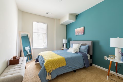 A bedroom with a blue bedspread and a yellow throw.