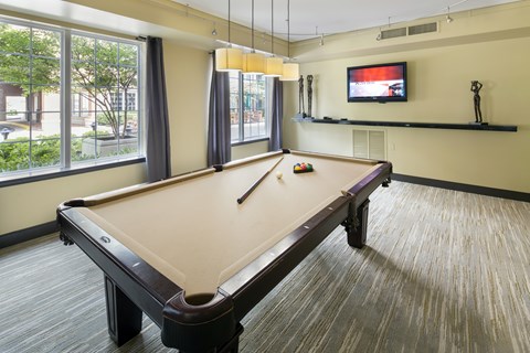 A pool table in a room with a television and a window.