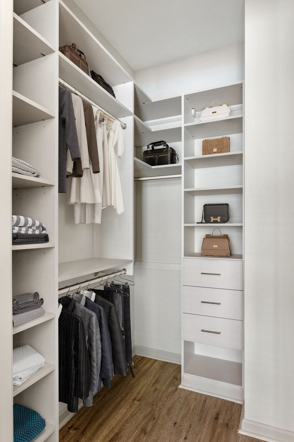 a walk in closet with white cabinets and shelves