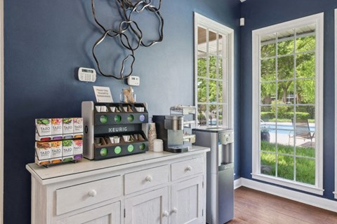 a kitchen with blue walls and a counter with coffee machines and a window