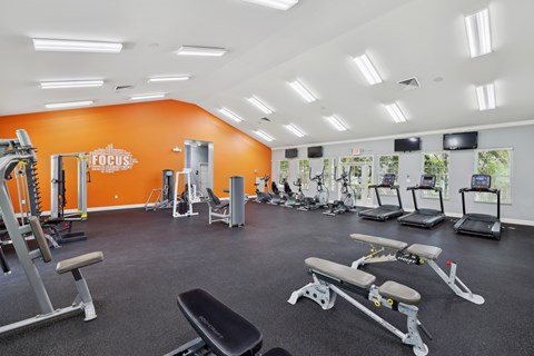 A gym with orange walls and a variety of equipment.