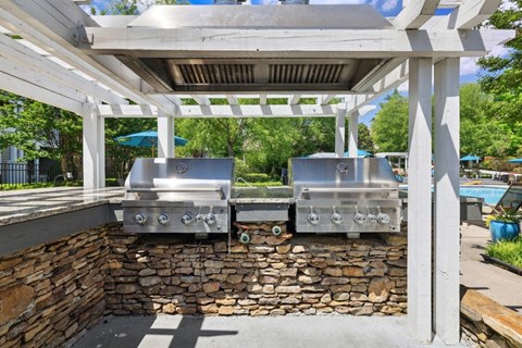 two stainless steel bbq grills on a stone wall under a pavilion