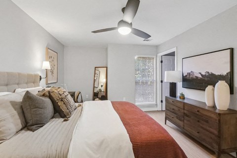 A bedroom with a large bed and a ceiling fan.