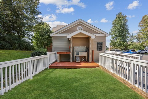 A small building with a porch and a white picket fence in front.