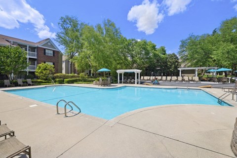 a swimming pool with trees and a building in the background