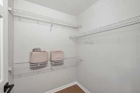 A white closet with two towels on the shelf.