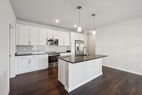 A modern kitchen with white cabinets and a black countertop.