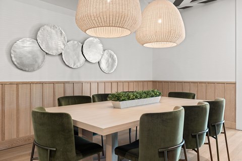 A conference room with a long table and green chairs.