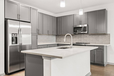 A modern kitchen with a stainless steel refrigerator and microwave.