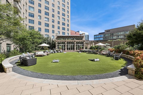 A large grassy area surrounded by buildings and trees.