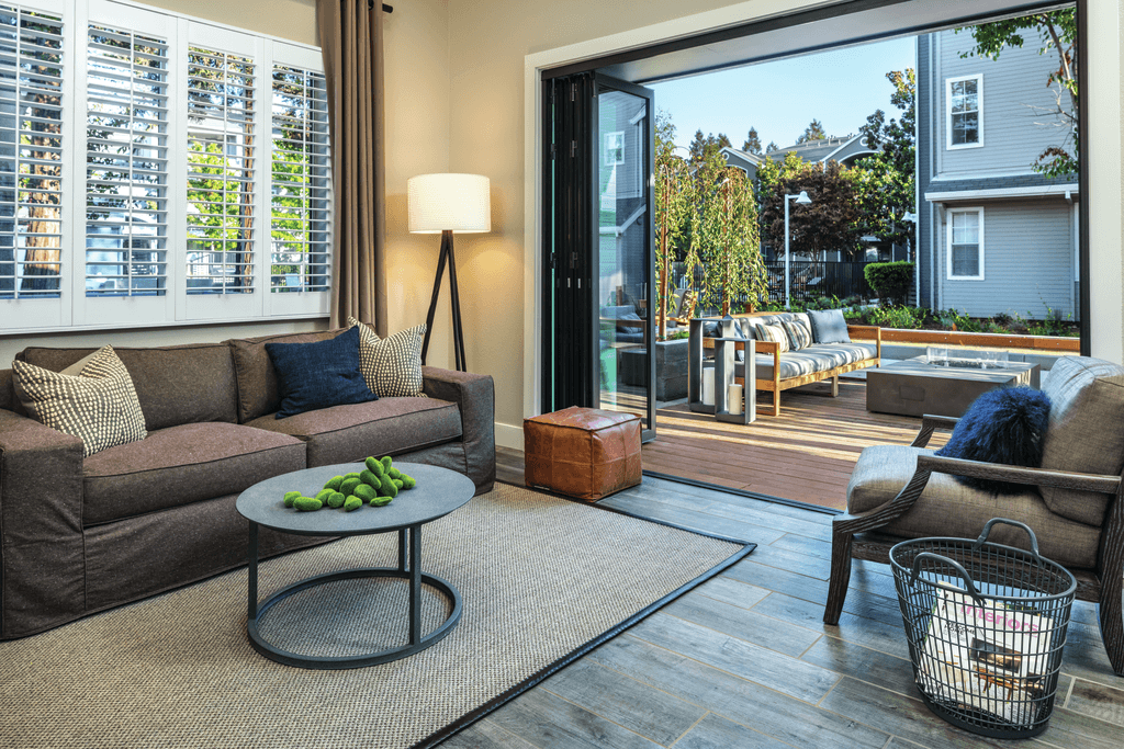 A living room with a couch, a coffee table, and a view of the backyard through a glass door.