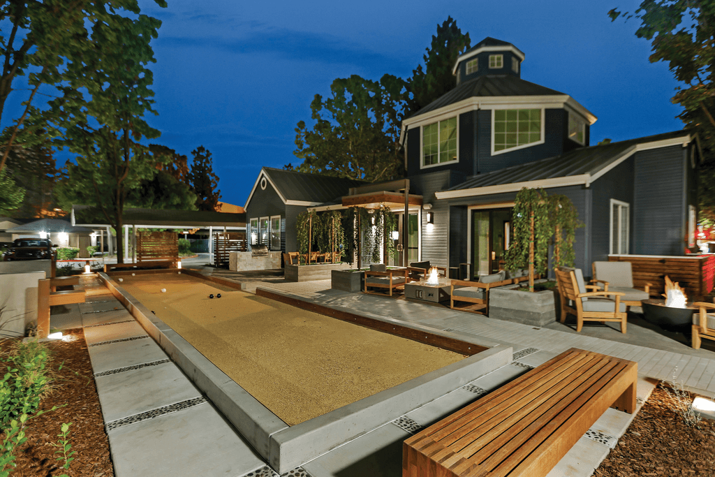 A modern house with a large backyard and a sand pit.