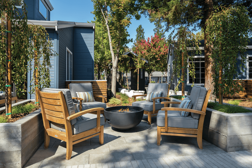 A patio with a fire pit and chairs.