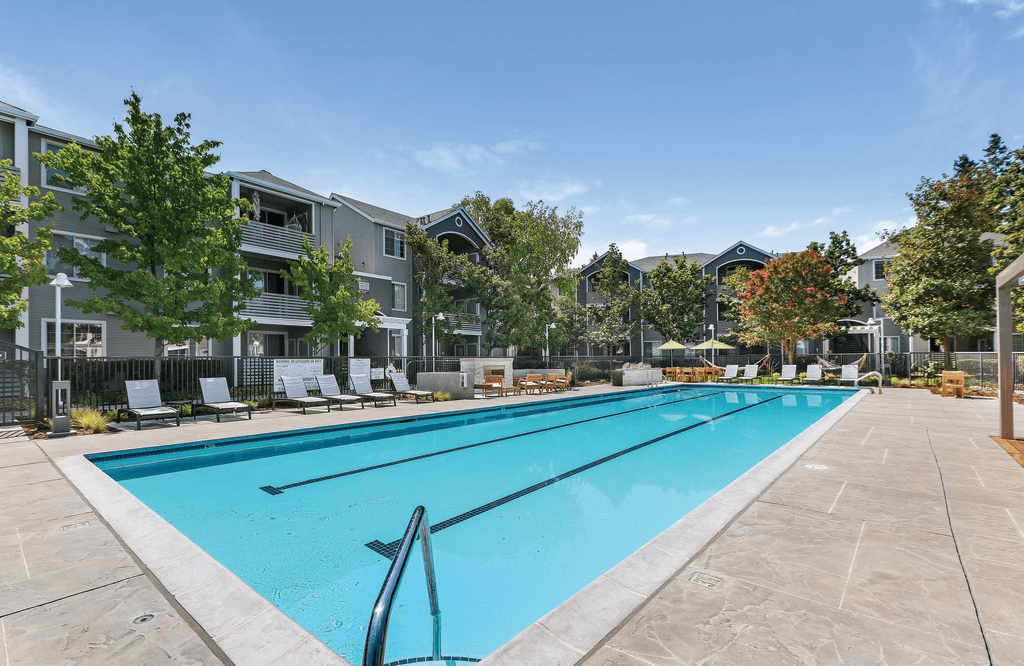 A large swimming pool in front of apartment buildings.