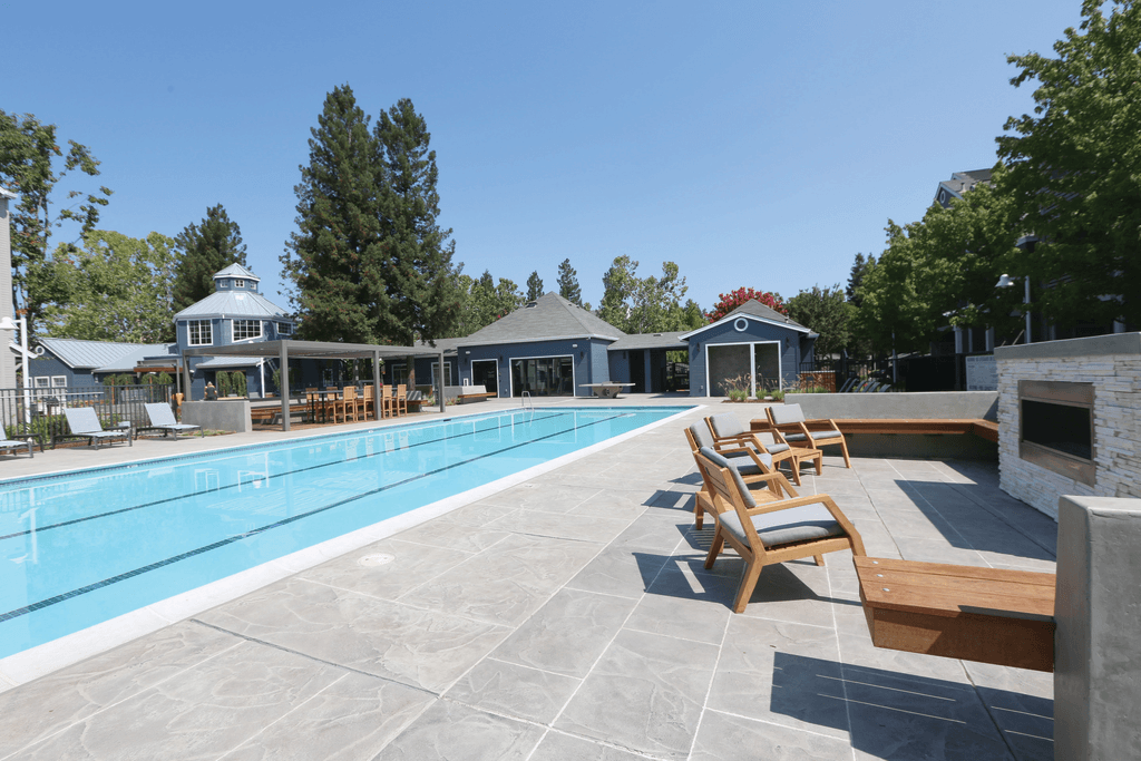 A large outdoor swimming pool with sun loungers and a pavilion.