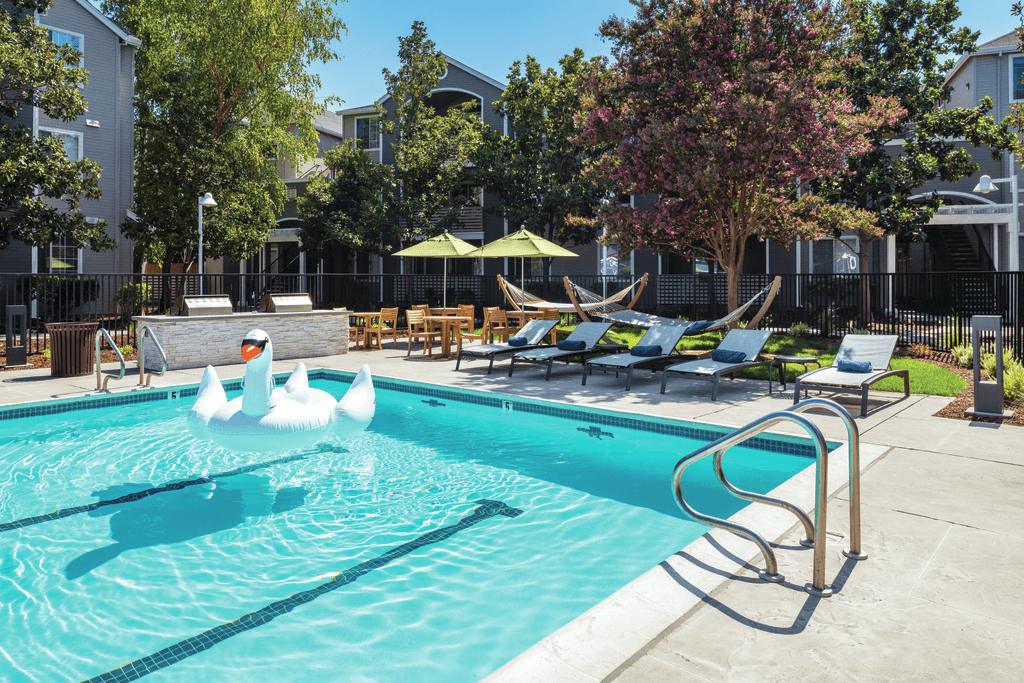 A swimming pool with a diving board and lounge chairs.