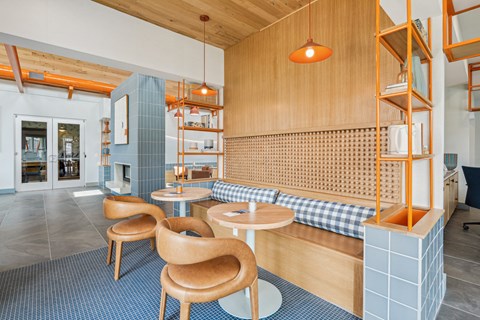 a lounge area with wooden tables and chairs and a blue tiled floor