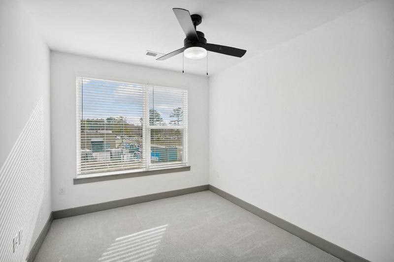 an empty bedroom with a ceiling fan and a window