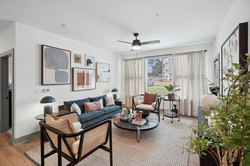 a living room with a couch and chairs and a ceiling fan