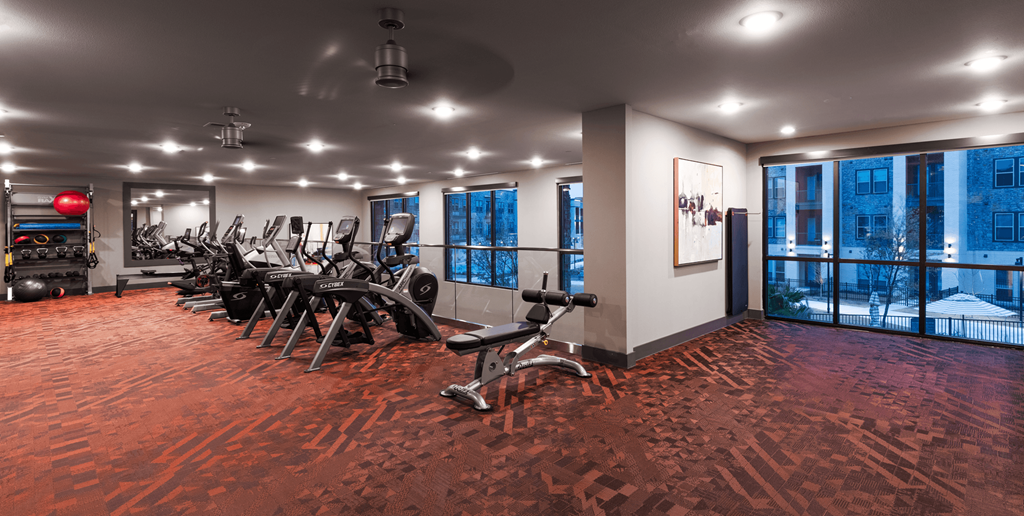 a workout room with exercise machines and windows in a building