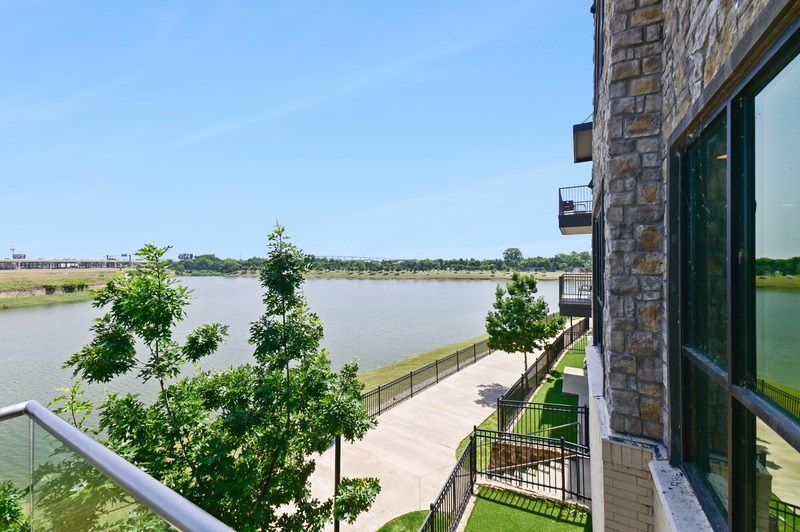 A balcony overlooks a body of water with a tree in the foreground.