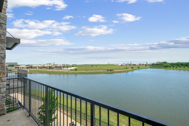 A balcony overlooks a calm body of water with a distant cityscape.