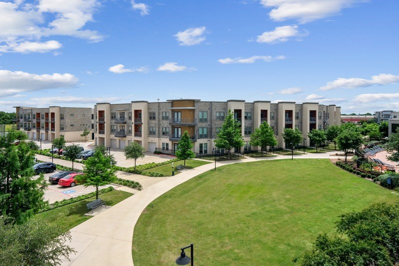 A large building complex with a green lawn in front.
