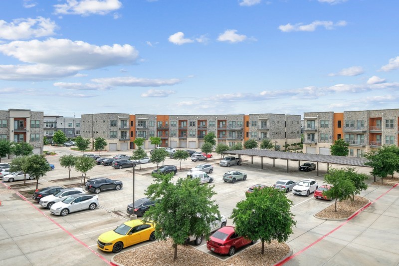 A parking lot with cars and a yellow car in the foreground.
